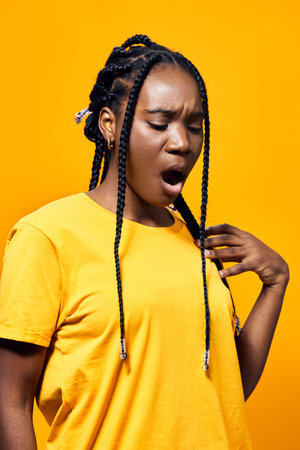 A young woman with long braided hair expressing boredom while wearing a vibrant yellow t shirt...