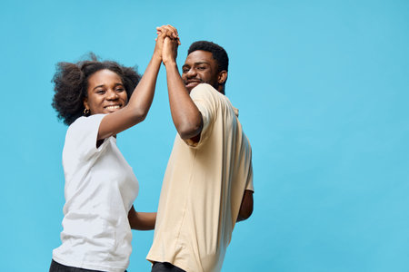 Happy couple dancing together against a blue background, expressing joy and love with vibrant emotions and casual summer attireの写真素材