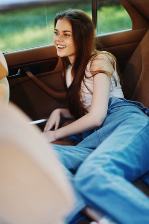Young woman relaxing in a car, wearing casual clothes with long hair, smiling joyfully in a serene outdoor setting, embodying a carefree lifestyle.の写真素材