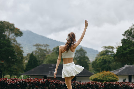 A young model in athletic wear joyfully poses outdoors, embracing a carefree mood amidst lush...