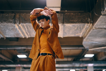 Stylish young man in a brown suit poses confidently under an industrial ceilingの写真素材