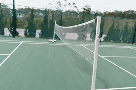 Empty tennis court with net and green surface, ideal for training and leisure activities, showcasing...
