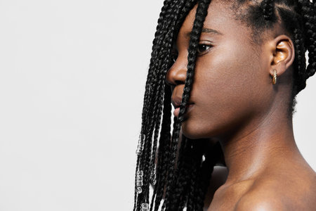Portrait of a young Black woman with braided hair, showcasing confidence and beauty against a minimalistic pastel background, perfect for beauty and fashion conceptsの写真素材