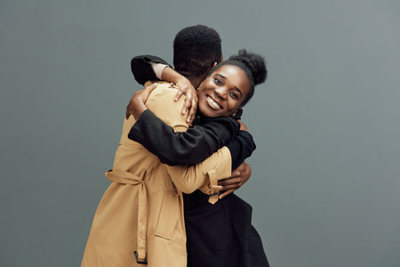Two joyful models embracing each other, showcasing friendship and warmth in stylish outfits against...