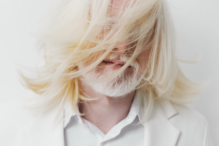 portrait of a man with long white hair, wearing a light suit, against a minimalistic white background, embodying elegance and modern styleの写真素材