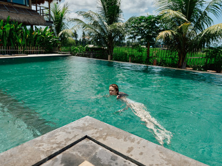 Tropical paradise woman enjoying a refreshing swim in a pool surrounded by lush palm trees