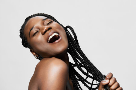 Joyful Black woman with braided hair expressing happiness, showcasing vibrant energy and confidence...