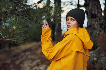 A woman in a yellow raincoat standing in the peaceful woods near a majestic pine treeの写真素材