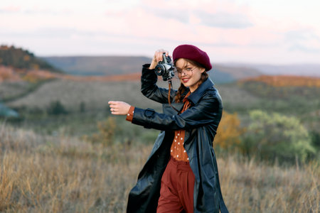 Woman capturing breathtaking mountain landscape with camera in scenic field settingの写真素材