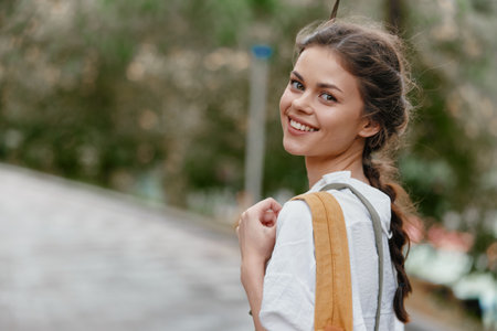 Cheerful young woman with a natural smile wearing casual white clothing and holding a tote bag,...