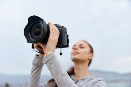 Young woman confidently taking photos outdoors with a professional camera, wearing casual sportswear, exuding creativity and enthusiasm, perfect for photography enthusiastsの写真素材