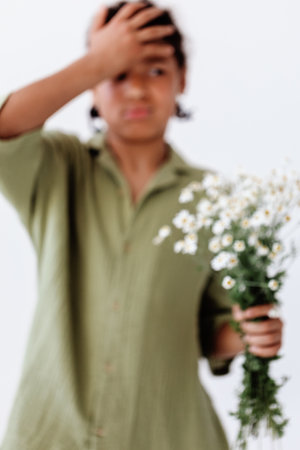 Woman holding a vibrant bouquet of daisies against a minimalist white wall backdropの写真素材