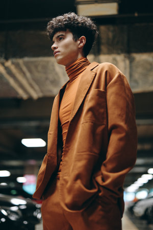 Stylish young man in a brown suit standing confidently in a modern parking garageの写真素材