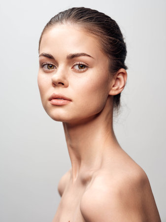 Young woman with flawless skin and elegant beauty posing in front of a gray backgroundの写真素材