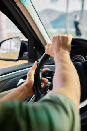 Hands gripping the steering wheel of a car from the driver s perspective, showcasing focus and control A blurred landscape is visible outside the windowの写真素材