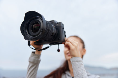 A young woman capturing stunning outdoor moments with a professional camera, showcasing her passion for photography in a serene natural settingの写真素材