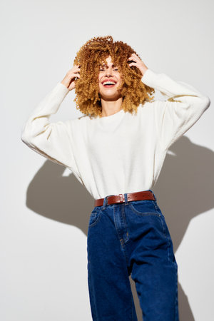 woman smiling in white sweater with curly hair on light background, casual fashion, joyful...