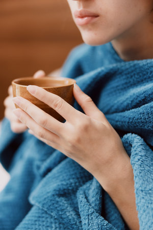 Young woman in blue towel holding cup of tea in front of her faceの写真素材