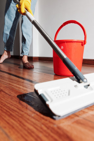Woman cleaning wooden floor with bucket and mopの写真素材