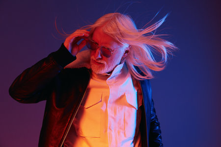 Stylish older man with long white hair and sunglasses, wearing a leather jacket, against a gradient...