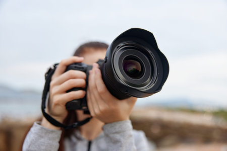 A young female photographer capturing nature scenes with a DSLR camera, showcasing passion and creativity in a serene outdoor settingの写真素材