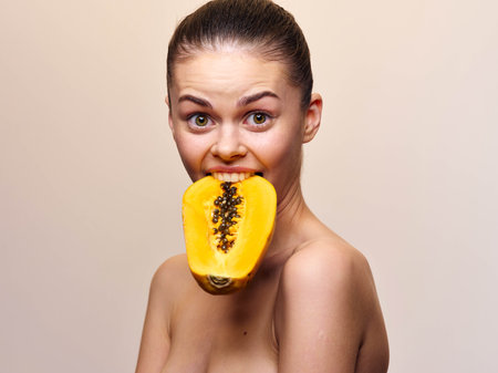 Beautiful woman holding a papaya fruit in front of her mouth, isolated on white backgroundの写真素材