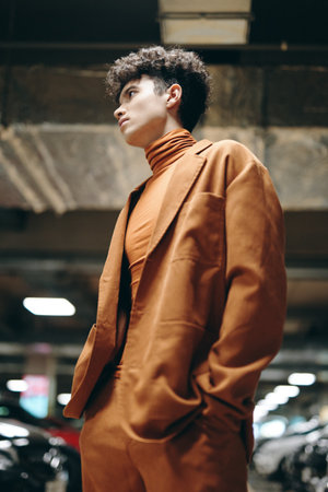 Stylish young man in a brown suit and turtleneck, standing confidently in a parking garage Modern urban vibe with muted colorsの写真素材