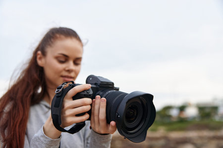 Young woman focused on capturing stunning photography with a DSLR camera outdoors in nature, showcasing a passion for creativity and exploration in photographyの写真素材