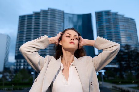 Confident businesswoman standing outdoors with a modern skyline in the background, showcasing professionalism and empowerment in a stylish outfit.の写真素材