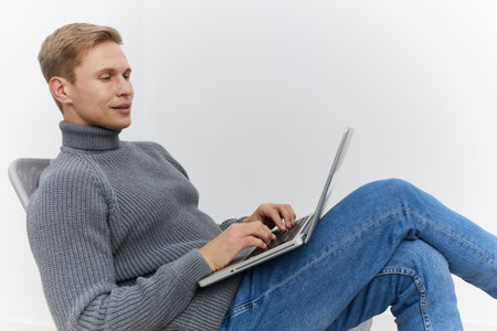 relaxed man using laptop casual wear sitting modern chair digital nomad remote work technology...