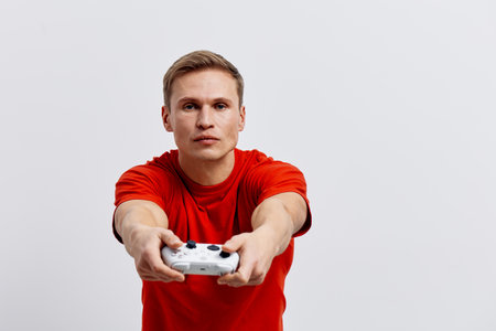 young caucasian man hold video game controller wear red t-shirt focused look camera isolated on...