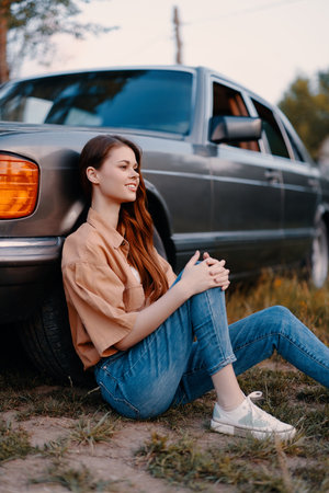 Young woman sitting by a vintage car in casual attire, showcasing a relaxed vibe and comfortable...