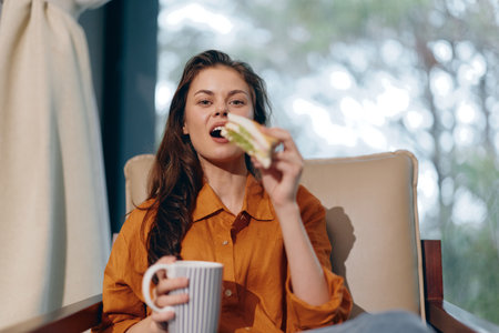 Young woman enjoying healthy sandwich and coffee in cozy indoor setting, showcasing vibrant colors and casual style, representing healthy eating and relaxationの写真素材