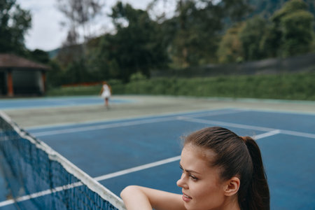 Athletic young woman enjoying a moment of contemplation on a tennis court, showcasing passion for healthy lifestyle and sportsの写真素材