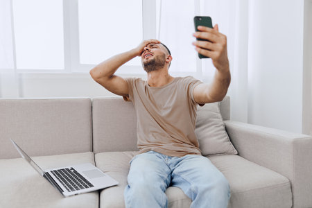 Frustrated man struggling with technology while video calling, showcasing the challenges of remote...