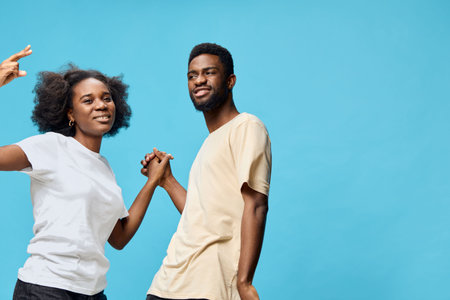 Two young, diverse models dancing joyfully against a vibrant blue background, showcasing happiness...