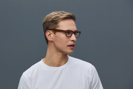 young caucasian man wear glasses white t-shirt look side isolated on gray background studio portrait...
