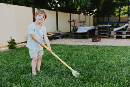 Young boy playing in the garden, enjoying outdoor activities, cheerful atmosphere, sunny day, green grass, child gardening.の写真素材
