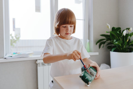 Young boy engaged in creative play, working with toys and exploring imagination in a bright, cheerful indoor space filled with greenery and natural light.の写真素材