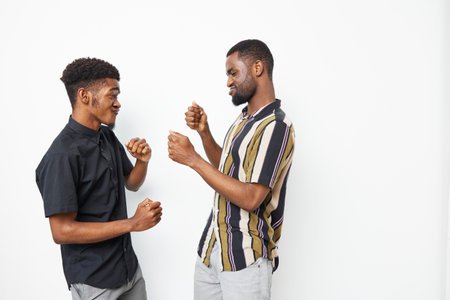 Two smiling African American men engaging in a joyful interaction, showcasing friendship and camaraderie in a playful atmosphere, perfect for social themes.の写真素材