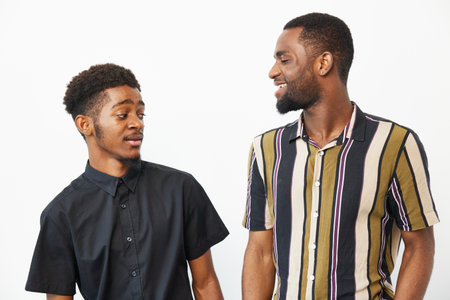 Two smiling African American men engage in a friendly conversation, showcasing joy and camaraderie...