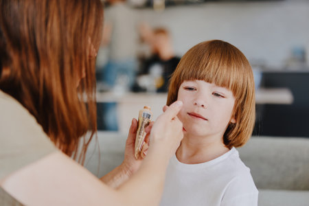 Caring woman applying makeup on a young girls face, showcasing a warm and loving moment filled with creativity and family bonding in a cozy setting.の写真素材