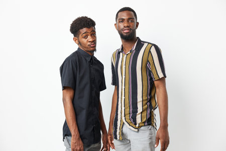 Two black men standing together, showcasing their unique styles and friendship, with an expressive, candid mood that highlights their personality and confidence.の写真素材