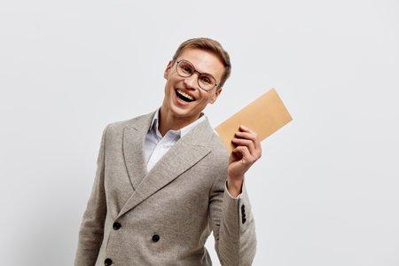 happy man holding envelope smiling in beige jacket isolated on plain light background digital detox concept emotion communicationの写真素材