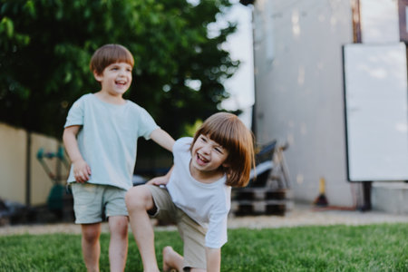 Happy children playing outdoors, enjoying a sunny day while laughing and playing in a grassy backyard, capturing the essence of childhood joy.の写真素材
