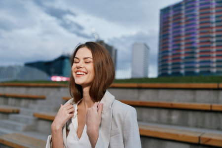 Young woman in light blazer smiling outdoors in urban setting with relaxed happiness and natural expression, casual fashion style, spring or autumn seasonの写真素材