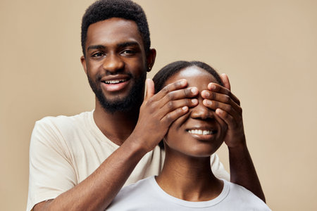 Happy couple playfully covering each other s eyes, showcasing love and connection against a neutral background, perfect for romantic themes and relationshipsの写真素材