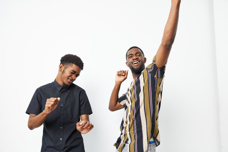 Two joyful black men dancing together, showcasing happiness and friendship. Their stylish outfits reflect a vibrant energy and a carefree spirit.の写真素材