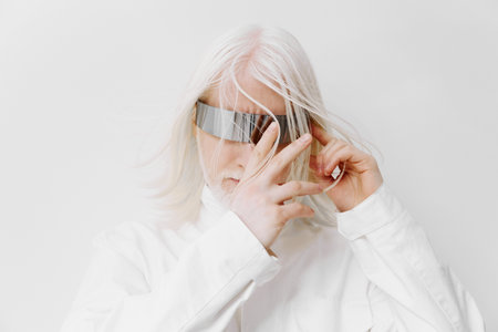 modern futuristic portrait, white background, person with silver reflective eyewear, long light hair, stylish fashion, minimalist concept, unique aesthetic, fashion statement, individuality expressedの写真素材