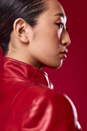 Fashion asian woman in red leather jacket posing on a red background